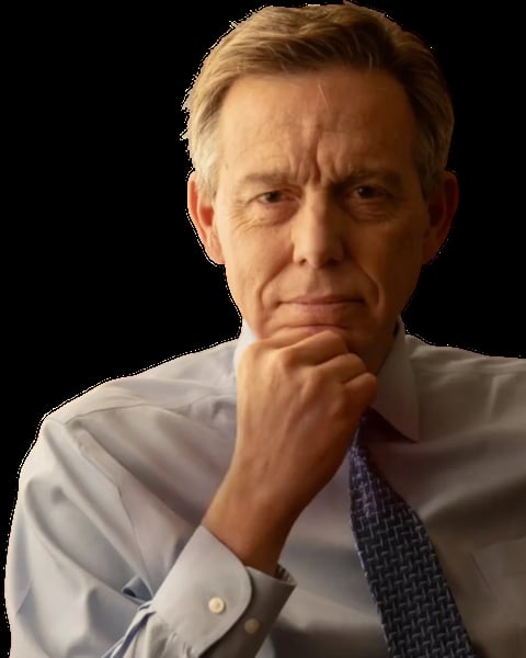 Middle-aged man in light blue shirt and dark tie, resting chin on hand with a thoughtful expression against a black background.
